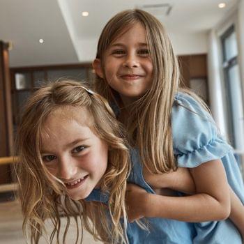 For families Smiling sisters playing together indoors in natural light
